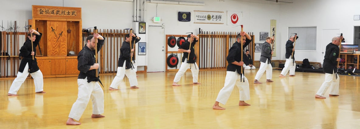 a group practicing Kobudo weapons in a dojo