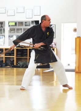 a person practicing kobudo weapons in a dojo